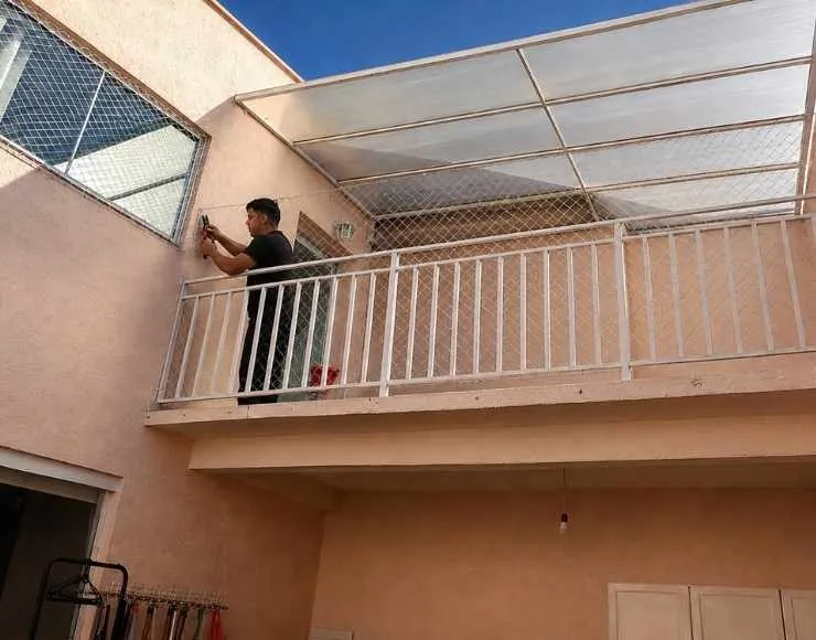 Técnico instalando rede de proteção em sacada de apartamento